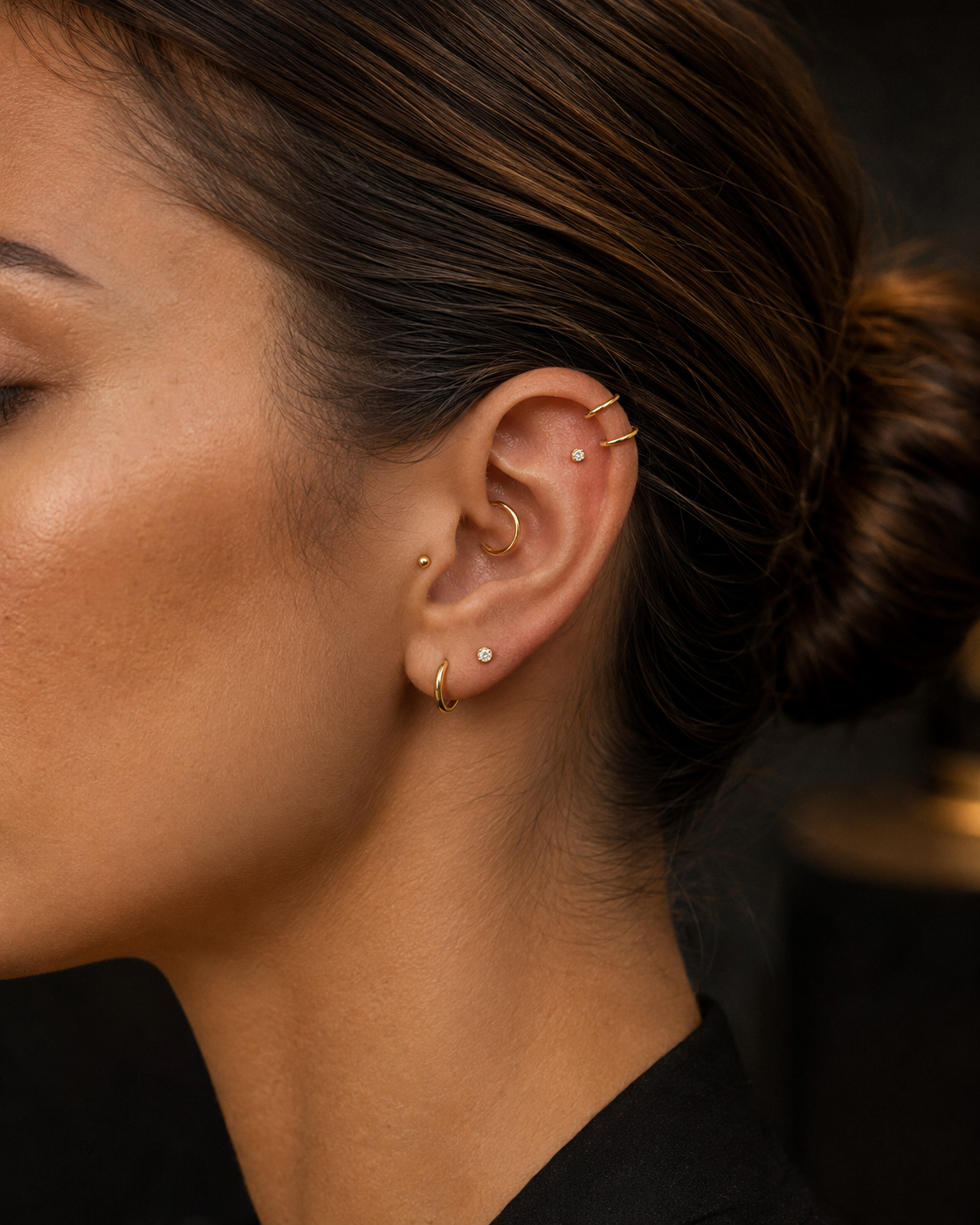 Oreille ornée de plusieurs bijoux de piercing en titane doré